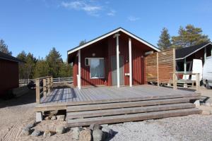 a cabin with a wooden deck in front of it at Rantasumppu 14, mökki viilennyksellä in Hailuoto