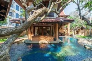 una casa con una piscina con un albero di fronte di MamaLek Boutique Pattaya Poolvill 20m to Beach a Na Jomtien