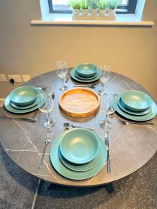 a table with plates and wine glasses on it at Stylish 2 Bed Apartment Derby in Derby