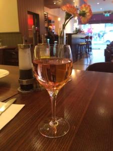 a glass of wine sitting on a wooden table at Kings Cross Inn Hotel in London