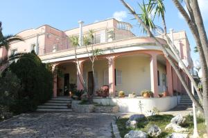 Villa la Bifora by Salento com في كاسترينيانو دل كابو: منزل وردي أمامه أشجار نخيل