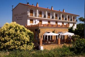 un bâtiment avec des tables et des parasols devant lui dans l'établissement Hostal Las Rumbas, à Nuévalos