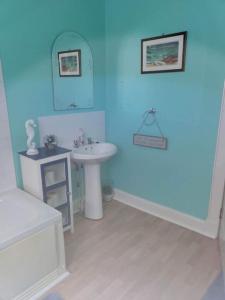 a blue bathroom with a sink and a mirror at Homely Apartment near the Beach with Mini Luxuries in Methil