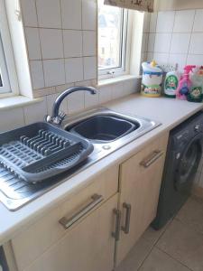 a kitchen counter with a sink and a washing machine at Homely Apartment near the Beach with Mini Luxuries in Methil