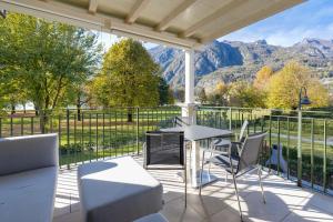 a porch with a table and chairs and mountains at Residence Porto Letizia - Happy Rentals in Porlezza