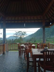 a restaurant with tables and chairs and a view of a mountain at Khailash Warung and Home Stay in Sidemen