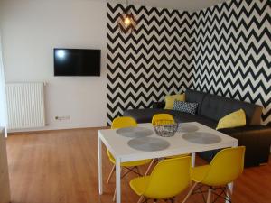 a living room with a white table and yellow chairs at Viktória Beach Apartman Gold 1. Siófok in Siófok