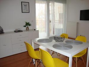 a kitchen with a white table and yellow chairs at Viktória Beach Apartman Gold 1. Siófok in Siófok