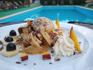a plate of food with ice cream and fruit at Vila EPIC in Costinesti