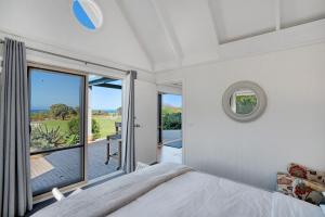 ein Schlafzimmer mit einem Bett und einem großen Fenster in der Unterkunft Bear Gully Coastal Cottages in Walkerville