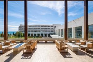 eine große Lobby mit Stühlen und einem Gebäude in der Unterkunft Eurostars Sitges in Sitges