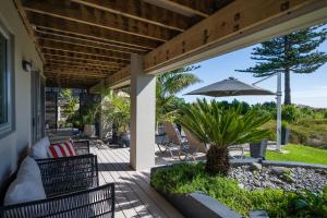 a patio with two chairs and an umbrella at Absolute Beach in Mount Maunganui