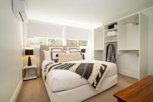 a white bedroom with a bed and a window at Absolute Beach in Mount Maunganui