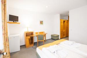 a bedroom with two beds and a desk and a tv at Hotel garni Zwickau-Mosel in Mülsen