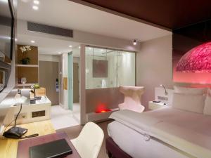 a bedroom with a bed and a desk and a bathroom at Pullman Eindhoven Cocagne in Eindhoven