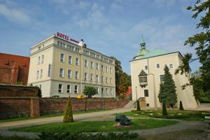 a white building with a red sign on top of it at Hotel Zamkowy in Słupsk
