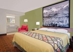 a hotel room with a large bed and a red chair at Super 8 by Wyndham Denver Central in Denver