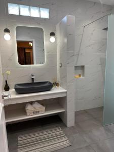 ein Bad mit einem Waschbecken und einem Spiegel in der Unterkunft SUNSENSES Villa in Angairiá