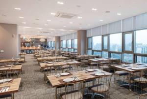 a dining room with tables and chairs and windows at Ramada Encore by Wyndham CheonAn in Cheonan