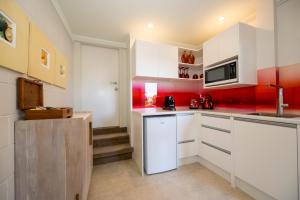 a kitchen with white cabinets and red walls at Absolute Beach in Mount Maunganui