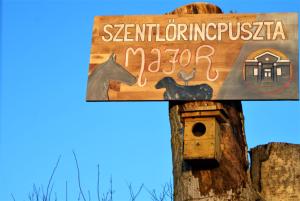 un cartel en un poste con una casa de pájaros en Szentlőrincpuszta Major, 