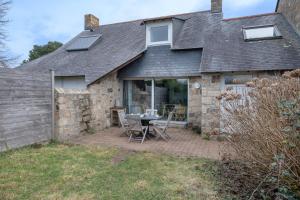 アルゾンにあるMaison pour 5 à quelques pas de la plage !のテーブルと椅子のあるパティオのある家