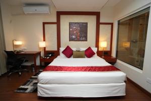 a hotel room with a large bed with red pillows at The Altruist Business Hotel Hitech in Hyderabad