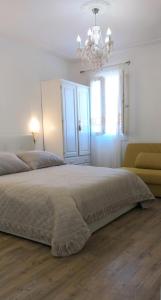 a white bedroom with a large bed and a chandelier at Cà Comare Burano in Burano