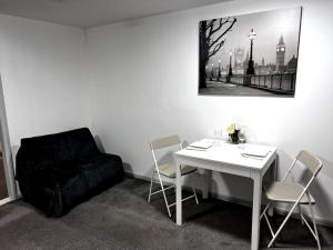 a room with a white table and chairs and a black chair at Studio flat in Sawbridgeworth in Sawbridgeworth