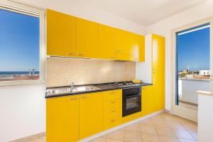 uma cozinha amarela com um lavatório e uma janela em Salentoandmore - Villetta Lecci em Salve