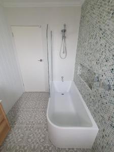 a white bath tub in a bathroom with a shower at Saltwater Cottage in Windang +8 photos
