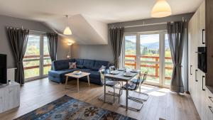 a living room with a blue couch and a table with chairs at Holiday Mountain Residence, Sun & Snow in Świeradów-Zdrój