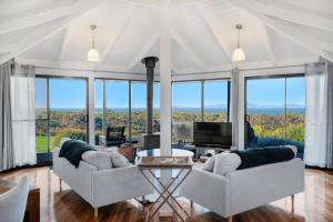 a living room with two chairs and a table and windows at Limosa Rise in Yanakie