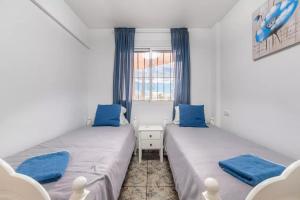 - 2 lits dans une petite chambre avec des oreillers bleus dans l'établissement 040 Apartamento Norra, à Torrevieja