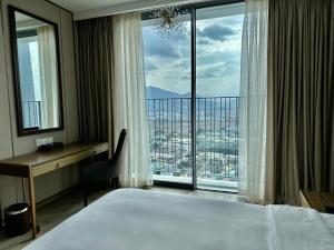 a bedroom with a bed and a desk and a large window at Handy Panorama Nha Trang Ocean view by HDG in Nha Trang
