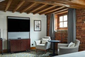 a room with a tv and chairs and a brick wall at Manchester Marriott Victoria & Albert Hotel in Manchester