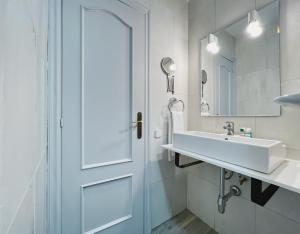 a white bathroom with a sink and a door at Stay U-nique Apartments GranDeGracia in Barcelona