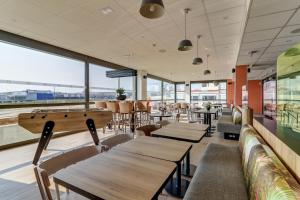 een restaurant met tafels en stoelen en grote ramen bij B&B HOTEL Dijon Valmy Toison d'or in Dijon