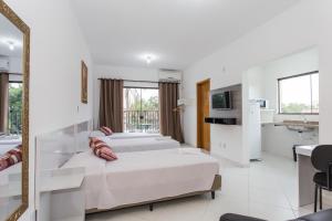 a white bedroom with two beds and a mirror at Domum Hotel in Pindamonhangaba