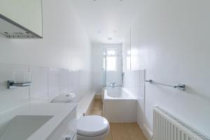 a white bathroom with a toilet and a sink at 2 Bedroom Apartment Close to Beach & Town Centre in Southend-on-Sea