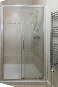 La salle de bains est pourvue d'une douche avec une porte en verre. dans l'établissement Tegfryn (Sleeps 8), 5*, Sea View, Borth y Gest, à Porthmadog