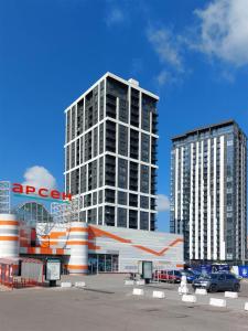 two tall buildings in a city with cars in front at VIP Апартаменти Червоної Калини,56а Сихів Новобудова in Lviv