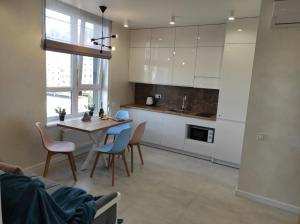 a kitchen with white cabinets and a table and chairs at VIP Апартаменти Червоної Калини,56а Сихів Новобудова in Lviv +5 photos