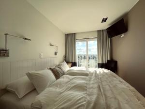 ウェンドゥイネにあるNEPTUNE Wenduine met zeezicht - VOSPROPERTIESのベッドルーム(大きな白いベッド1台、窓付)