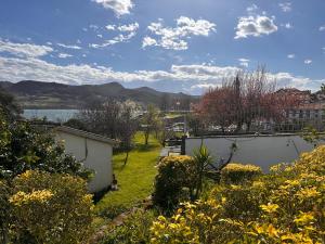 a garden with yellow flowers and a body of water at CASA AZUL SANTA KATALINA in Mundaka