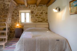 ein Schlafzimmer mit einem Bett in einem Zimmer mit Steinwänden in der Unterkunft Messinian Stone House in Messini