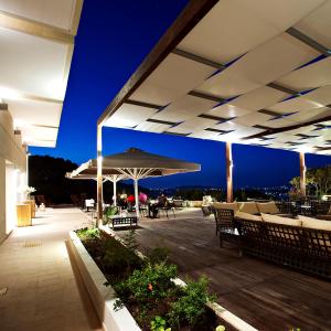 a patio with an umbrella and chairs and tables at Orizontes View Hotel in Katakolon