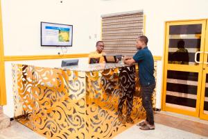 dos hombres parados en un mostrador en una habitación en E-Gold Luxury Hotel, Maitama en Abuja