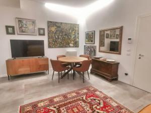sala de estar con mesa, sillas y TV en Rooms Corso Porta Nuova, en Verona