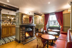 - un bar avec une cheminée, des tables et des chaises dans l'établissement The Kings Arms Hotel, à Keswick